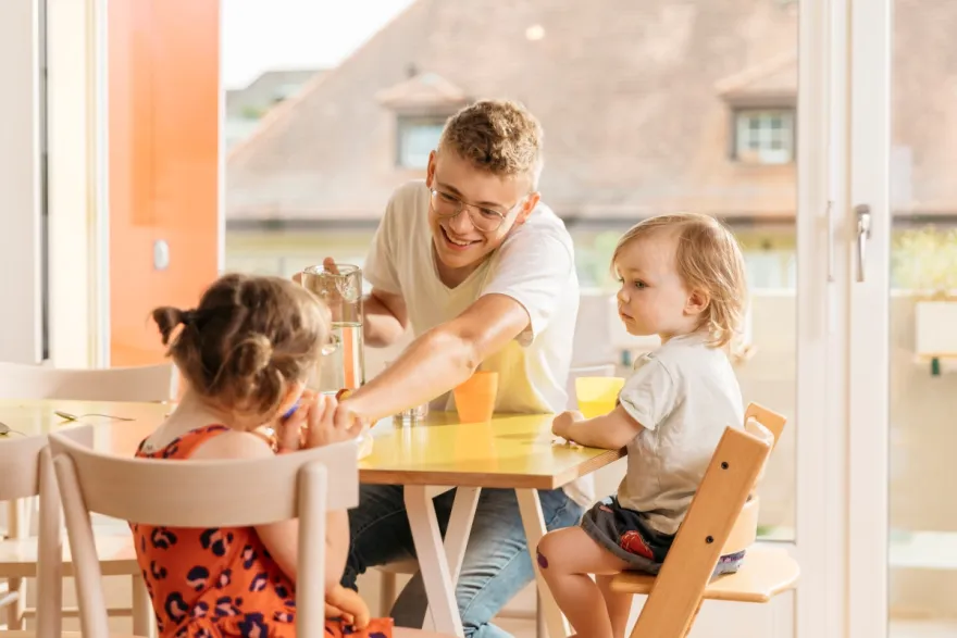 Babysitter isst mit den Kleinkindern Zvieri.
